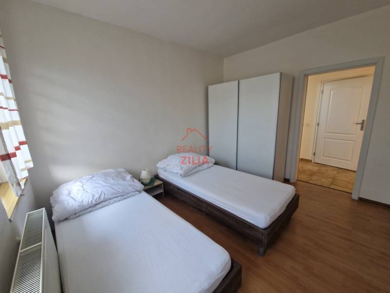 A room in a family house with two beds, a wardrobe, and a floor with a wooden decor.