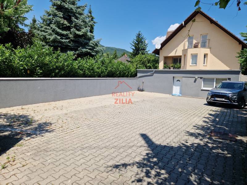 A family house on Jelenecká Street in Nitra with a landscaped yard and a car.