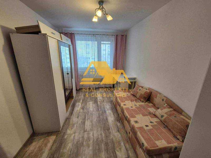 A room in a 3-room apartment with a sofa, a wardrobe, and a floor with a wooden decor.