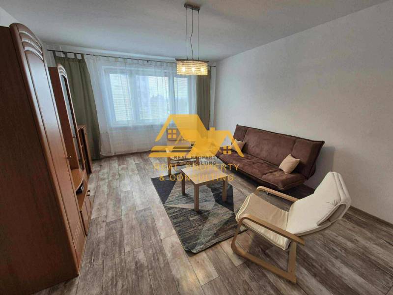 Living room in a 3-room apartment with a sofa, an armchair, and a wooden-patterned floor.