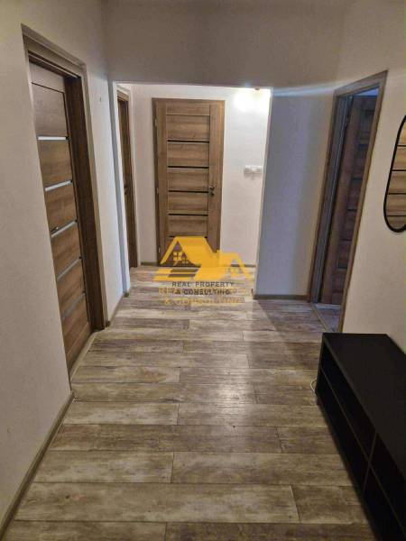 A hallway in a 3-room apartment with a wooden decor floor and multiple doors.