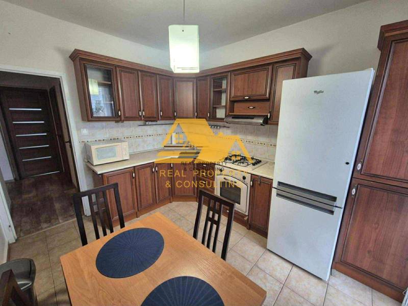 A kitchen with dark wood decor, a stove, and a refrigerator in a 3-room apartment.