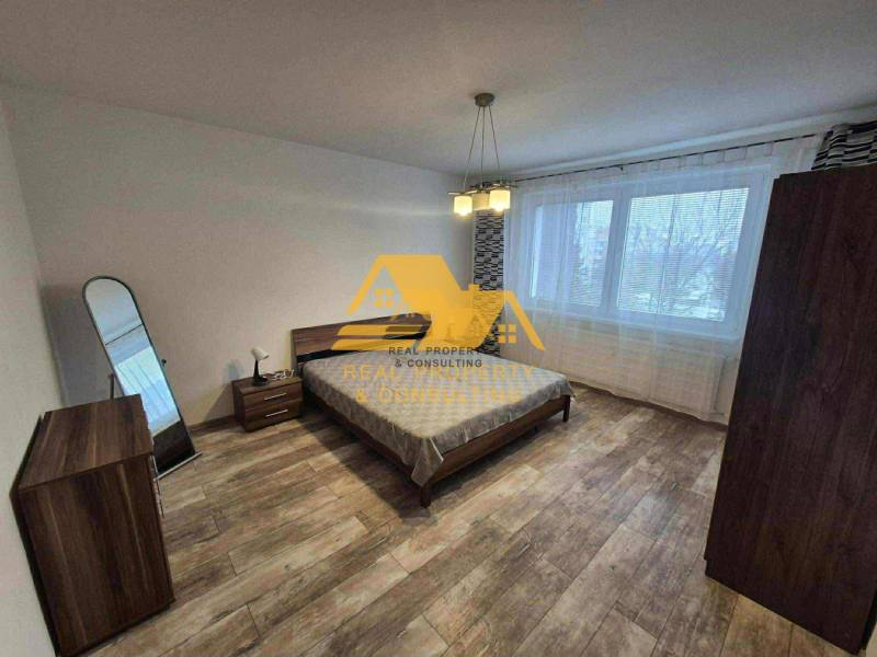 Bedroom in a 3-room apartment with a bed, mirror, and floor with a wooden decor.