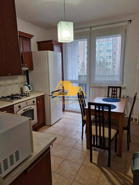 Kitchen in a 3-room apartment with a dining table and appliances, floor with wood decor.