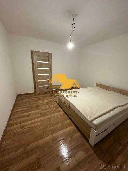 Bedroom in a 2-room apartment with a bed, wooden floor decor, and simple lighting.