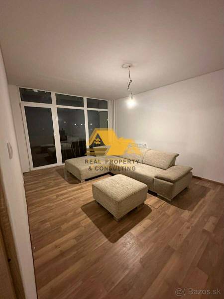Living room in a 2-room apartment with a sofa and a wooden decor floor.