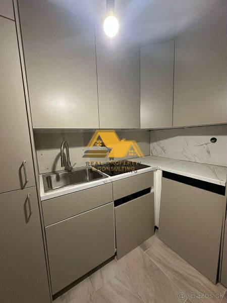 A kitchen in a 2-room apartment with a marble countertop and gray cabinets.