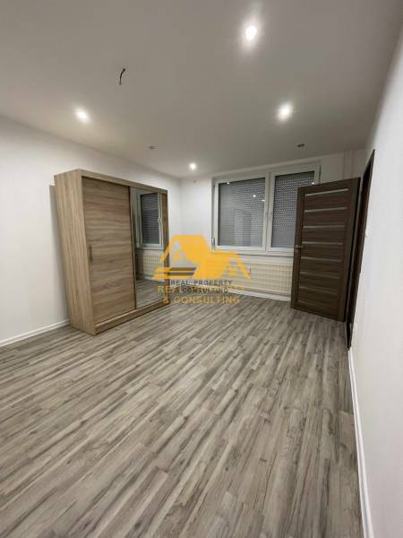 A spacious room with a sliding wardrobe and a wooden decor floor in a studio apartment.