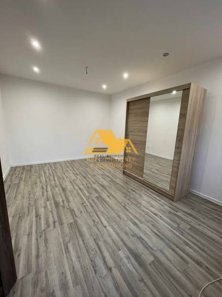 Interior of a 1-room apartment with a wood-patterned floor and a built-in wardrobe.
