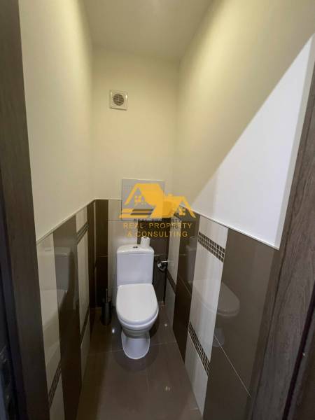A toilet with tiles and cladding in a studio apartment, hidden ventilation system.
