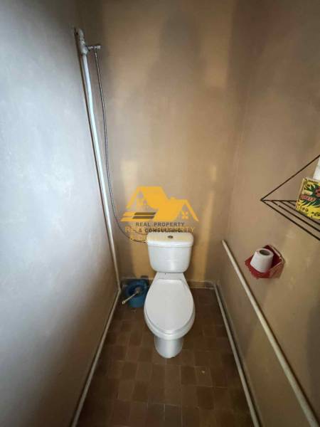 A bathroom in a family house with a toilet, shower, and brown tiles.