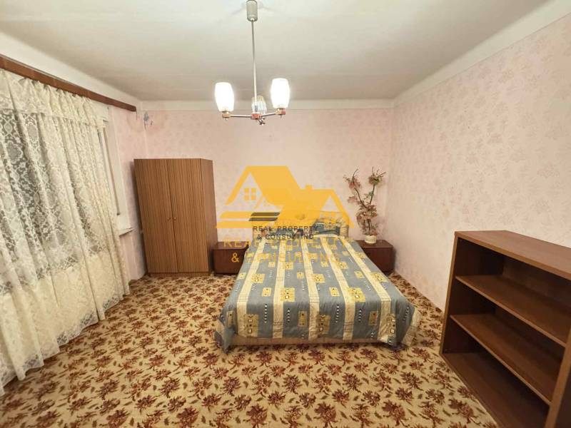 Bedroom in a family house with carpet and furniture, soft pink wallpaper.