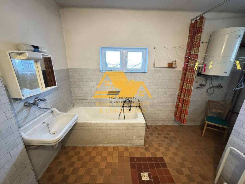 A bathroom in a family house with a bathtub, a sink, and a boiler.