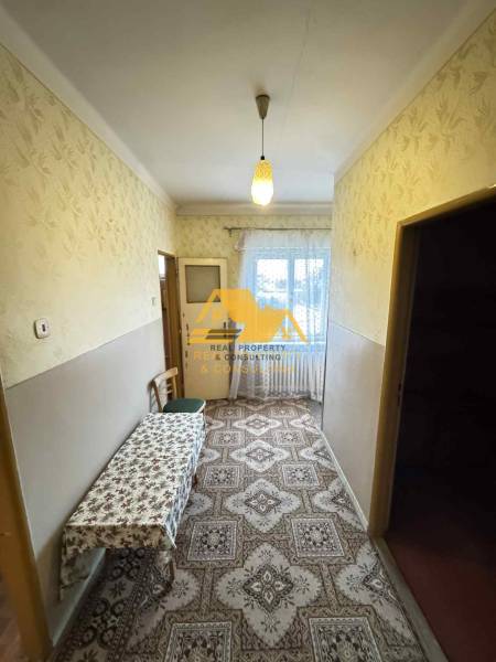 A hallway in a family house with carpet decor and a table, a window at the end of the room.