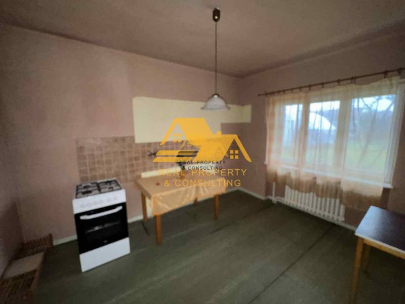 A kitchen in a family house with a stove, table, curtain, and light wall decor.