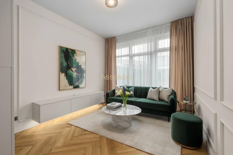 Living room with a green sofa, decorative table, and wood-patterned flooring.