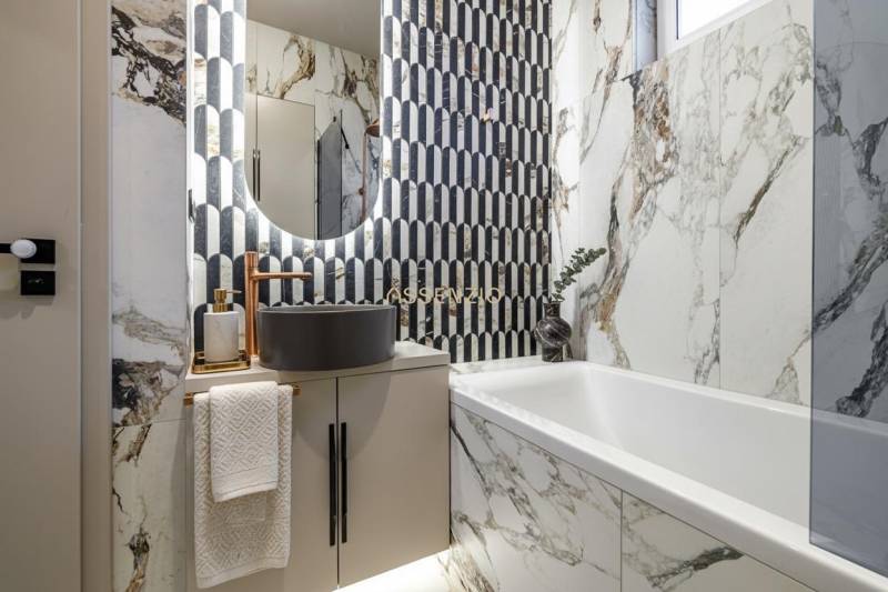 A bathroom in a 2-room apartment with marble tiles and a modern sink.