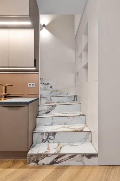 Marble stairs by the kitchen unit in a 2-room apartment, with a floor featuring a wooden decor.