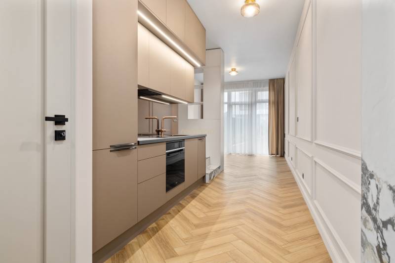 Kitchen in a 2-room apartment with a wooden decor floor and neutral colors.