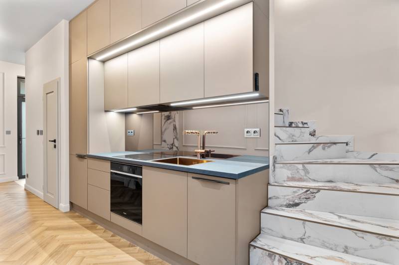 A kitchen in a 2-room apartment with a marble staircase and a wooden decor floor.