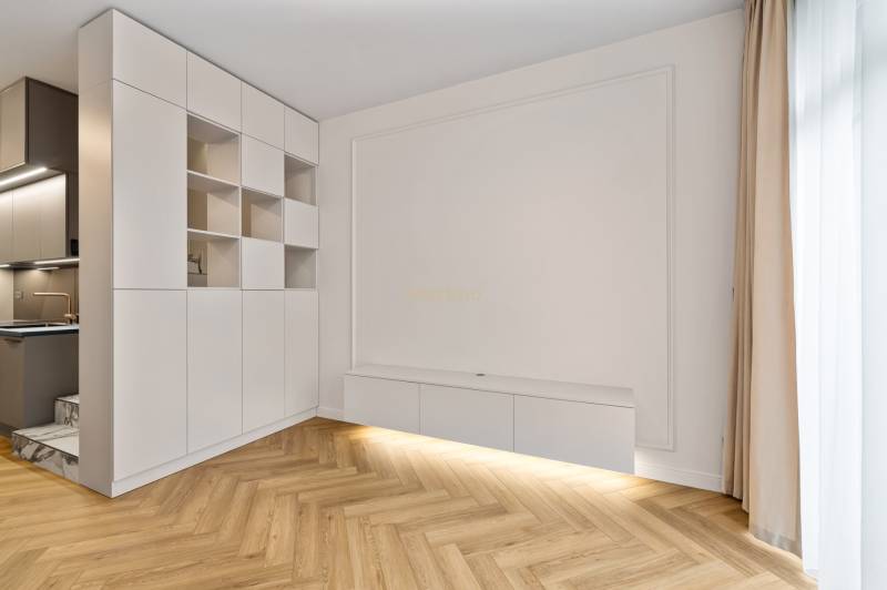 In the 2-room apartment, there is a white built-in wardrobe and a floor with a wooden decor.