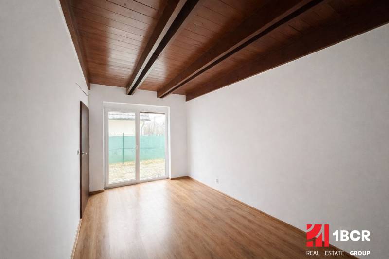 A room in a family house with a wooden decor floor and a large window.