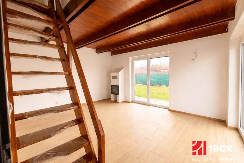 Interior of a family house with a staircase, fireplace, and wooden decor flooring.