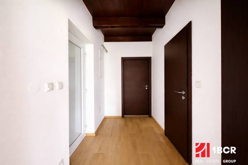 A hallway in a family house with a wooden decor floor and dark brown doors.