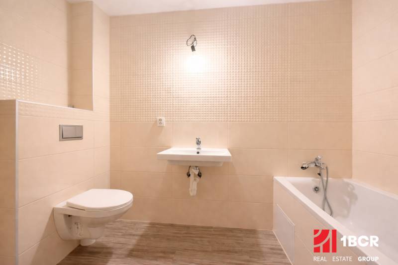 A bathroom in a family house with a bathtub, a sink, and a wooden decor floor.