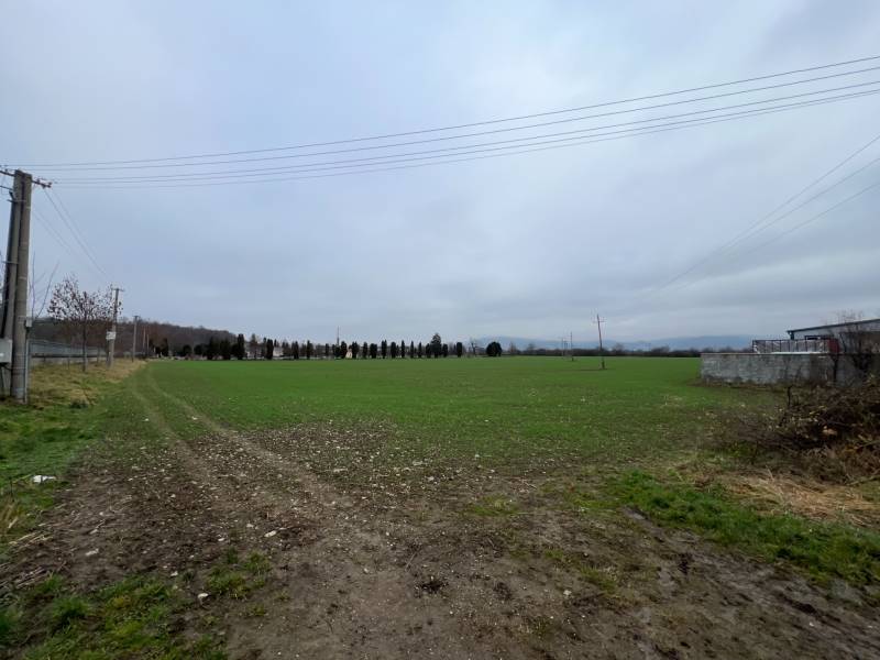 Commercial land in Pruské with power lines and green lawn under an overcast sky.