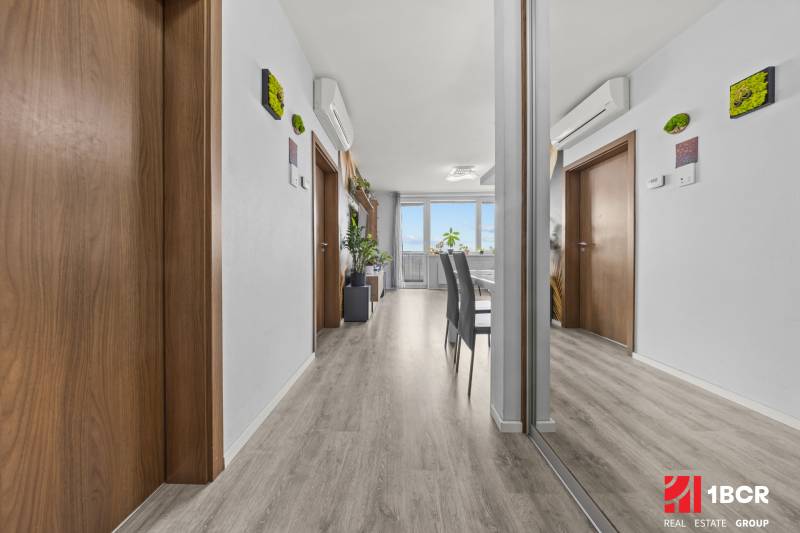 Interior of a 2-room apartment with wood-patterned flooring, a mirror, and air conditioning.