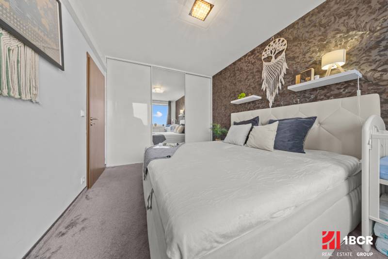 Bedroom in a 2-room apartment with a double bed, mirrored wardrobe, and wall decorations.