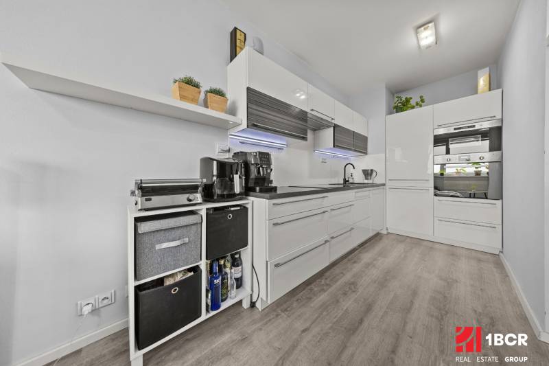 A kitchen in a 2-room apartment with white cabinets and a wood-patterned floor.
