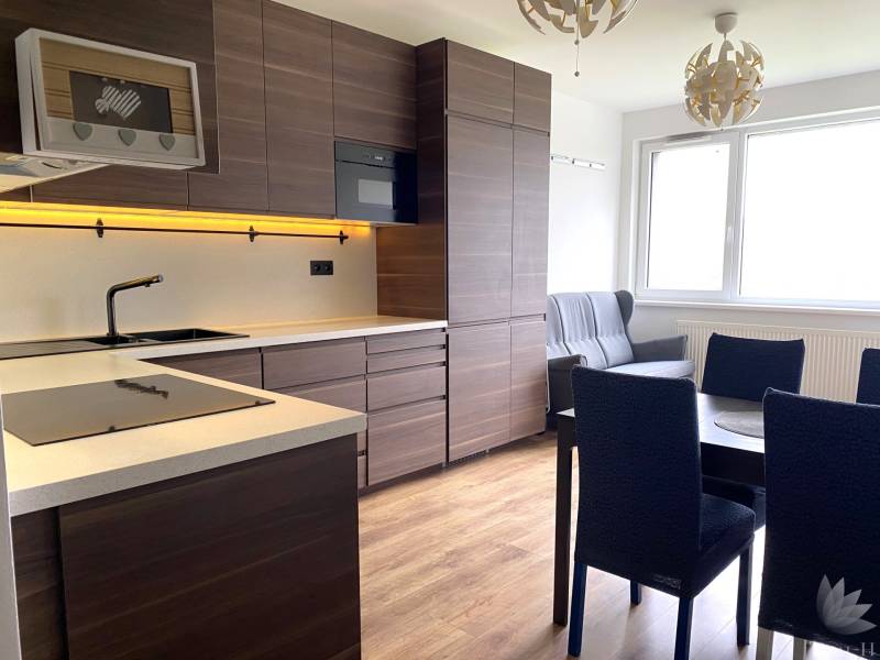 A kitchen in a 3-room apartment with dark furniture and a wooden decor floor.