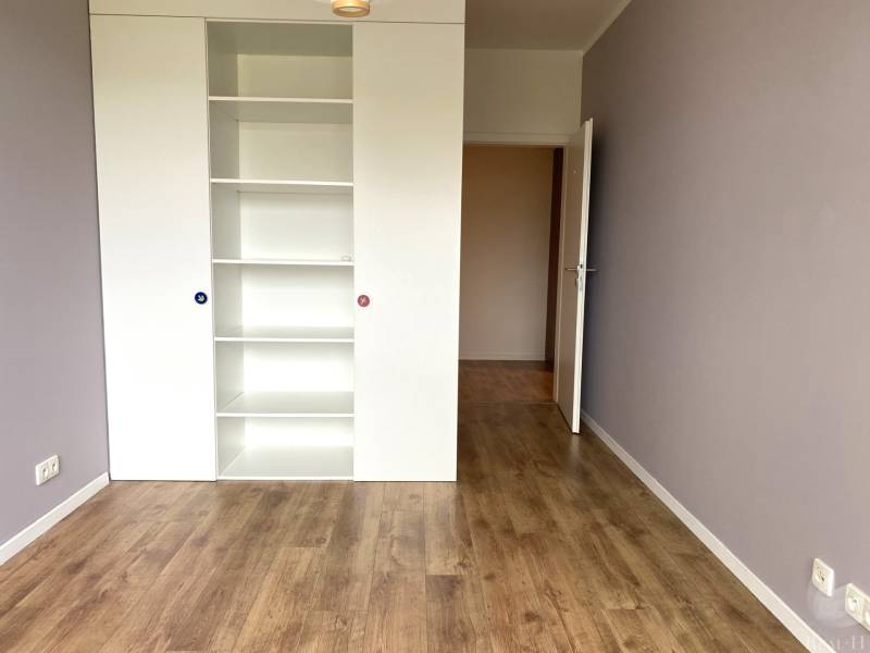 A room with a white shelf and a wooden decor floor in a 3-room apartment.