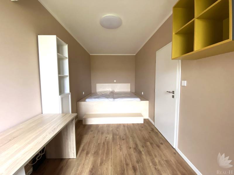 A room in a 3-room apartment with a wooden decor floor and a built-in desk.