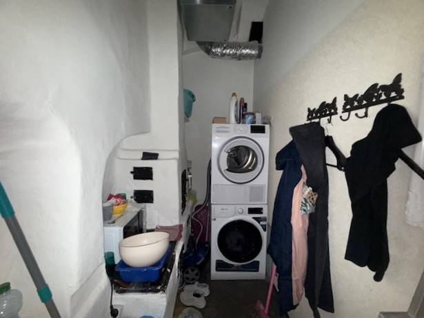 Laundry room with a washing machine, dryer, coats, and storage space in commercial premises.