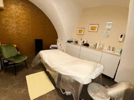 Massage table in commercial premises with vaulted ceiling, including accessories.