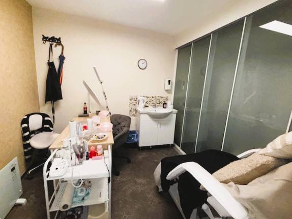 Beauty salon with a chair, table, and sink in commercial premises.