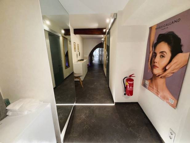 A corridor of commercial premises with a poster, wooden decor flooring, and a fire extinguisher.