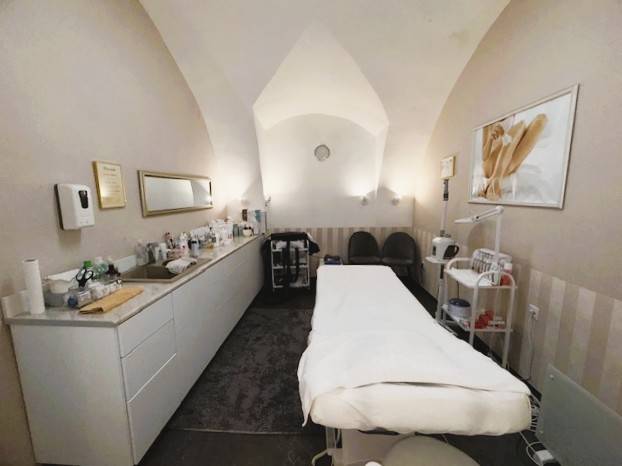 Commercial premises with a massage table, medical supplies, and a decorative painting on the wall.