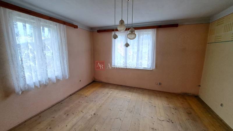 A room in a family house with two windows and a floor with a wooden decor.