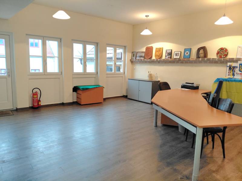 Offices with wood-patterned flooring, a desk, and decorations on a shelf.