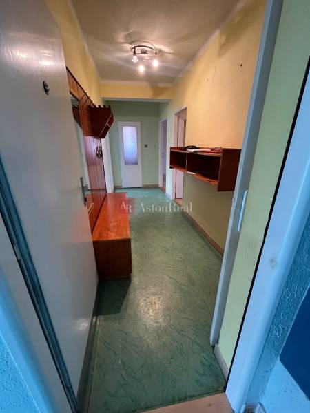 A hallway in a 3-room apartment with built-in furniture and a green floor.