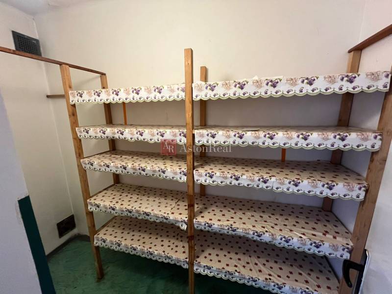 Storage space in a 3-room apartment with wooden shelves and a green floor.