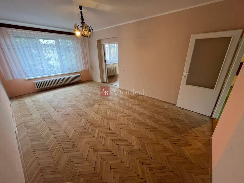 A spacious room in a 3-room apartment with a wood-decorated floor and a large window.