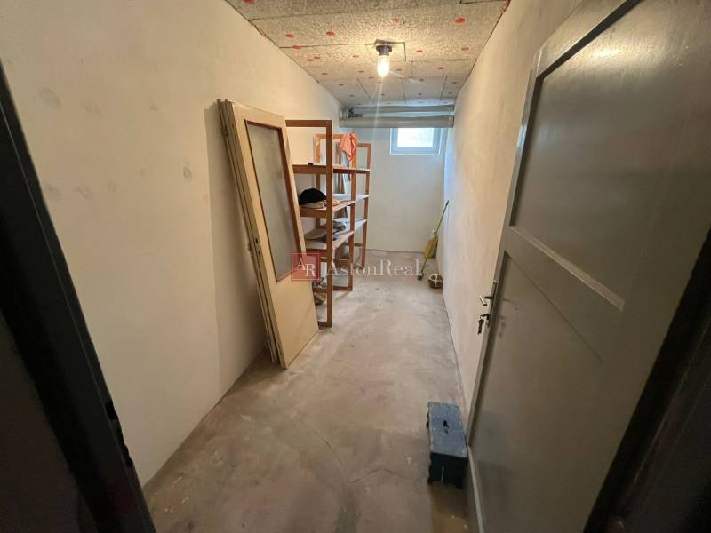 Storage space with shelves and a window in a 3-room apartment, without flooring.