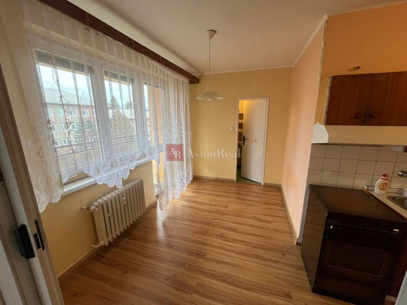 A kitchen with a wood-patterned floor, curtains, and a radiator in a 3-room apartment.