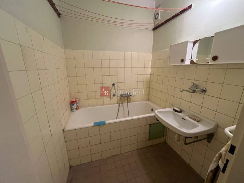 Bathroom in a 3-room apartment with a bathtub, sink, and tiled walls.
