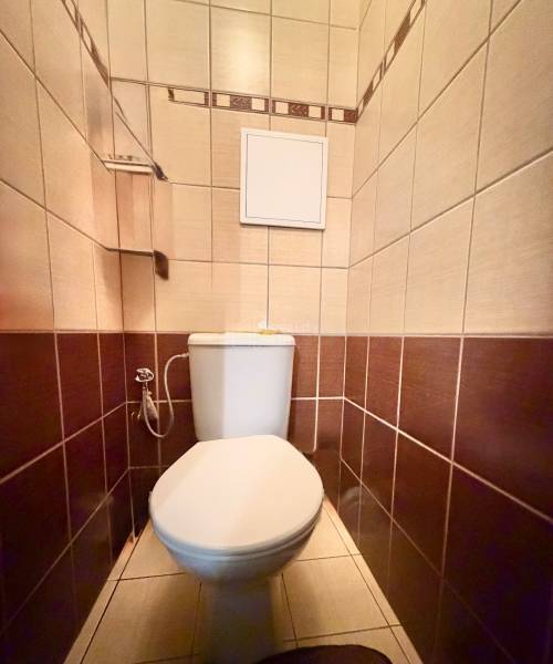 A bathroom with light and dark brown tiles in a 2-room apartment.